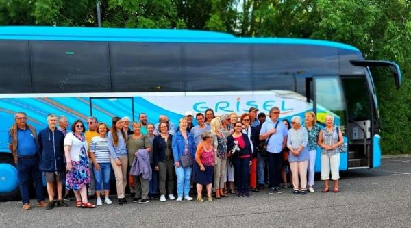 The touring party stand in front of a blue coach