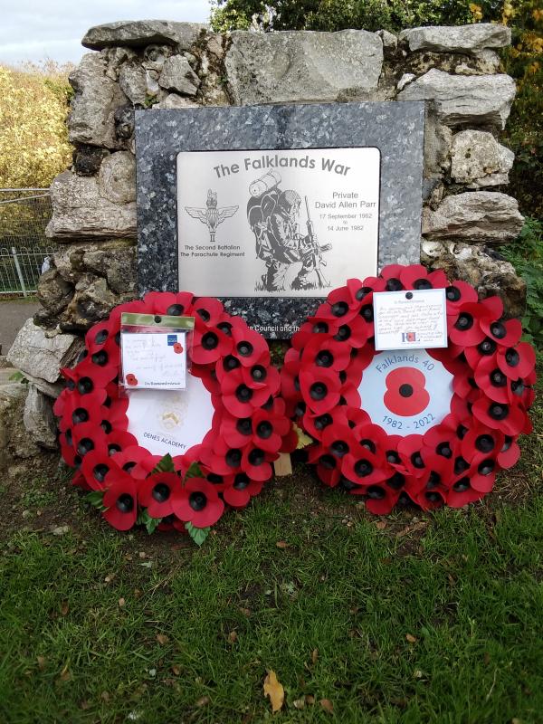 Two Poppy Wreaths lay in front of a Memorial Plaque to Private David Parr