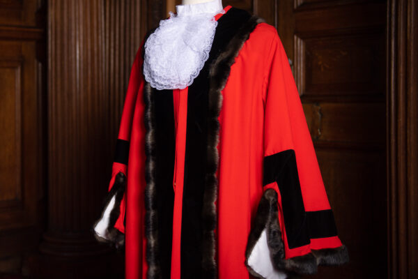 A red mayoral robe is displayed on a stand. It has dark fur lining