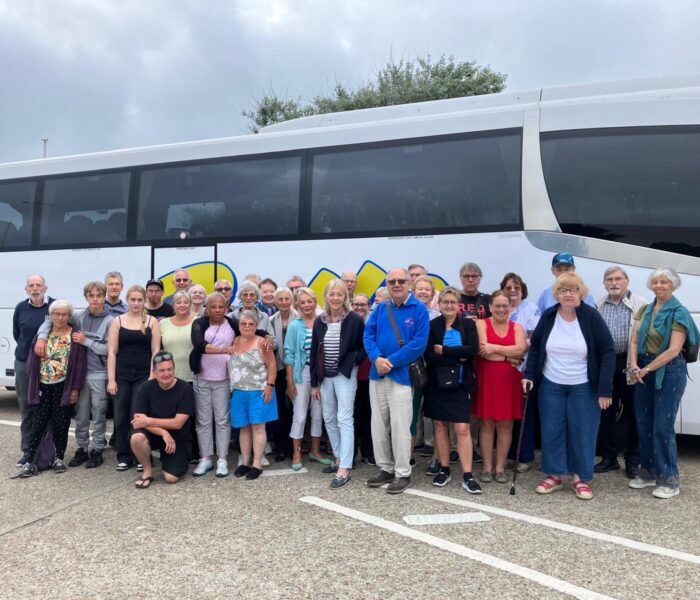 A large group of people gathered in front of a large group of large white coach