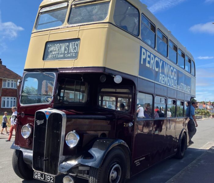 The picture shows a burgundy double-decker bus
