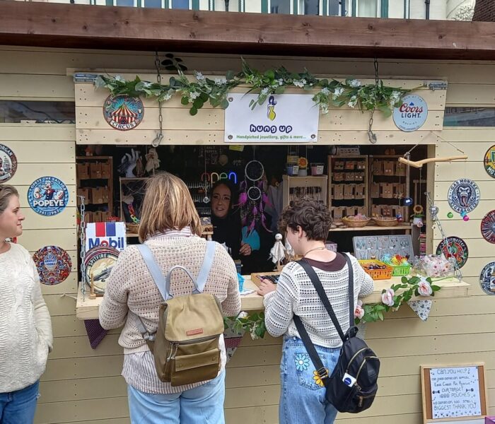 Three people approach a kiosk with their backs to the camera