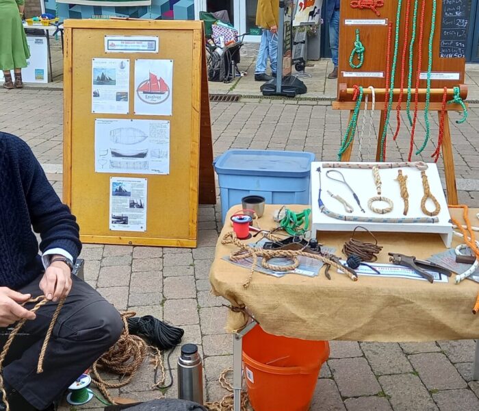 A person is sat tying knots into rope