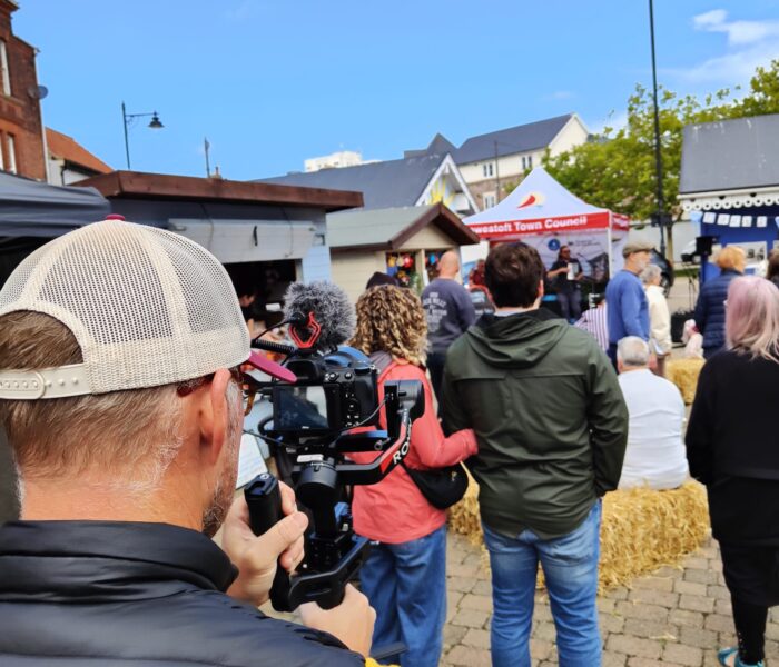 A crowd photo. In the foreground someone is filming