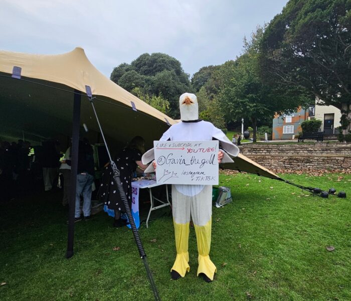 A person in a Seagull costume holding a sign