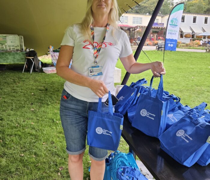 A person stands handing out blue bags