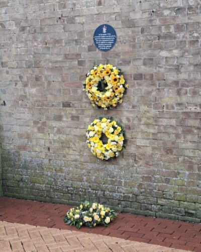 Image of two yellow commemorative wreaths hanging on a wall