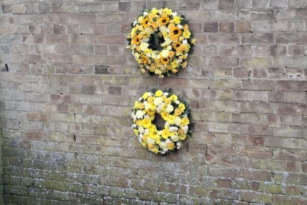 Image of two yellow commemorative wreaths hanging on a wall
