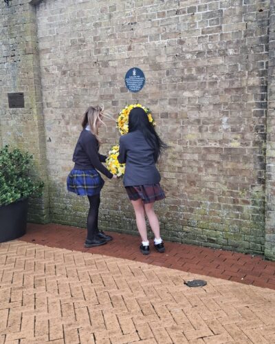 Image of two young people hanging a wreath on a wall