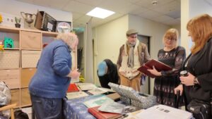 People stand either side of a table looking at pictures