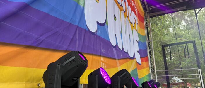A photo of stage lights under a large sign that reads Lowestoft Pride