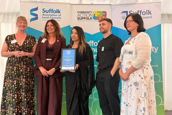 Photo of five people posing for a picture after being handed a certificate.