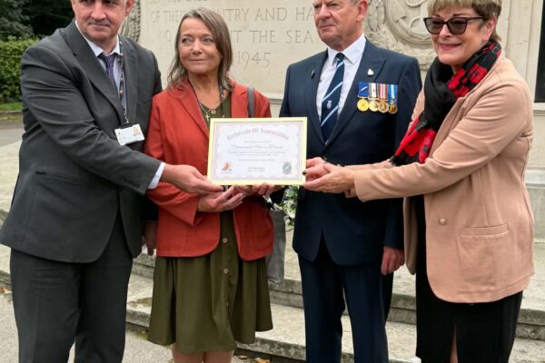 Four people stand hold a certificate